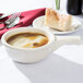 A Tuxton eggshell white bowl of French onion soup with bread.