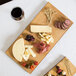 An American Metalcraft carbonized bamboo serving board with cheese and olives.