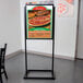 A black Aarco double sided freestanding sign holder with a pizza sign inside.