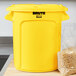 A yellow Rubbermaid BRUTE lid on a 10 gallon trash can.