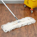 A Carlisle dry dust mop pad attached to a yellow mop.