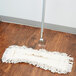 A white Carlisle dry mop pad on a wood floor.