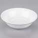 A white porcelain cereal bowl with a white rim on a white surface.