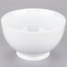 A close-up of a 10 Strawberry Street Classic White oval porcelain footed rice bowl with a white rim on a gray surface.