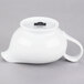 A white porcelain gravy boat with a handle and lid.