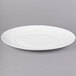 A white oval porcelain platter with a rim on a gray surface.
