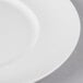 A close-up of a 10 Strawberry Street white porcelain luncheon plate with a white rim.