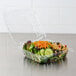 A salad in a Dart clear plastic container with a hinged lid.