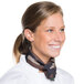 A woman in a chef's uniform smiling wearing a camouflage neckerchief.