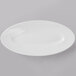 A close up of a 10 Strawberry Street Ricard white porcelain oval plate with a fork on a gray background.