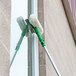 An Unger OptiLoc telescopic pole with a green and white ErgoTec locking cone on a window.