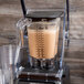 A Hamilton Beach blender with a brown liquid in it on a table.