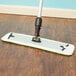 A Lavex microfiber mop with a green handle on a wood floor.