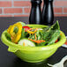 A bowl of salad with vegetables in a green Fineline plastic bowl.