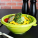 A green Fineline PET plastic salad bowl filled with salad on a table.