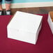 A white pie box on a red table.