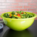 A green Fineline PET plastic bowl filled with salad on a table.