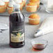 A bottle of Regal Gourmet Pure Vanilla Extract next to a bowl of liquid and cupcakes.