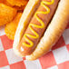 A hot dog with Woeber's mustard on top of a checkered tablecloth.