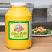 A yellow container of Woeber's yellow mustard on a counter next to a plate of salad.
