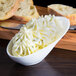 A white Arcoroc Lucido porcelain bowl filled with cream cheese on a table with bread.