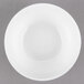 An Arcoroc white porcelain stackable bowl with a white rim on a gray surface.