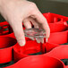 A hand using a red Carlisle glass rack extender to hold a glass.