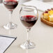 Two Acopa Bouquet wine glasses filled with red wine on a table.