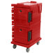A red Cambro insulated food pan carrier with black handles on wheels.