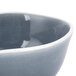 An Arcoroc blue porcelain bowl with a white background and a gray rim.