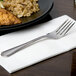 A 10 Strawberry Street Lincoln stainless steel salad fork on a napkin next to a plate of rice and chicken.