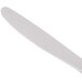 A white heavy weight stainless steel dinner knife with a gold plated handle.