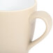 A beige stoneware mug with a white handle.