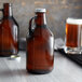 A brown Libbey growler filled with beer next to a glass of beer.