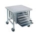 A stainless steel mobile mixer table with tray slides holding four trays.