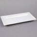 An American Metalcraft white rectangular stoneware platter on a gray surface.