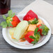 A Bare by Solo medium weight paper plate with a variety of fruit and a glass of juice on it.