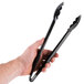 A hand holding a pair of black Cambro plastic tongs.