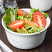 A white Cambro porcelain bowl filled with salad with tomatoes and carrots.