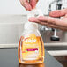 A person using a GOJO Fresh Fruit Foaming Antibacterial Hand Soap dispenser on a counter.