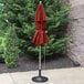 A Grosfillex terra cotta umbrella on a pole over a patio table.