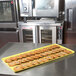 A yellow MFG Tray Supreme Display Tray holding cookies on a counter.