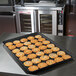 A black MFG Tray Supreme Display Tray with multicolored cookies on it sitting on a counter.
