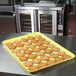 A yellow MFG Tray display tray with cookies on a counter.