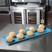 A MFG Tray sky blue fiberglass display tray holding muffins on a counter.