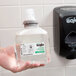 A hand holding a plastic bottle of GOJO Green Certified Foam Hand Soap.