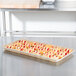A MFG Tray rattan fiberglass display tray of pastries on a table.