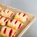 A MFG Tray Rattan Fiberglass display tray of pastries with strawberry jam.