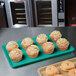 A tray of muffins on a MFG Tray mint green fiberglass market tray on a counter.