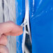 A hand holding a zipper on a blue Heavy Duty Bun Pan Rack Freezer Cover.